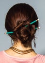 Pencils in head hair updo. back shot of brunet woman with two green pencils in her hair.
