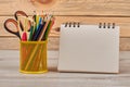 Pencils in metal basket and blank notebook.