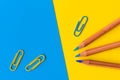 Pencils and paperclips against a blue and yellow background