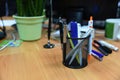 Pencils and pens  in plastic glass on the wooden table in the office. Plastic box for storing artificial objects, organizer for Royalty Free Stock Photo