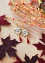 Pendant earrings on wooden table with autumn leaves decor