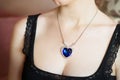 A pendant with a large blue gemstone in the shape of a heart hangs around the neck. Jewellery Royalty Free Stock Photo