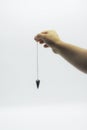 Pendulum dowsing on an isolated white background with an amethyst crystal