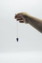 Pendulum dowsing on an isolated white background with an blue crystal and colored chakra stones