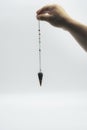 Pendulum dowsing on an isolated white background with a seven colored chakra crystal point