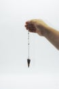 Pendulum dowsing on an isolated white background with an a seven colored chakra crystal point