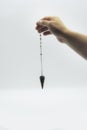 Pendulum dowsing on an isolated white background with a seven colored chakra crystal point