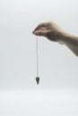 Pendulum dowsing on an isolated white background with a turquoise crystal