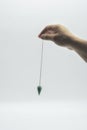 Pendulum dowsing on an isolated white background with a turquoise crystal