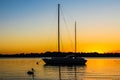 Penguin and sailboat flot in beautiful sunset colored water with reflections  under orange sky Royalty Free Stock Photo