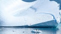 Penguins on ice floe in front of huge iceberg with one pengin on. Looks like penguins want to discover the iceberg. Antarctica