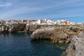 View of the jagged rocky coast and colorful houses in the center of Peniche