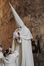 A penitent walks in front of a graffiti in the procession of Holy Week Royalty Free Stock Photo