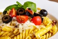 Penne and fusilli pasta with tomatoes, olive, parmesan and basil Royalty Free Stock Photo