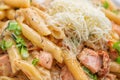 Penne pasta bolognese with parmesan, served on white plate