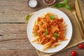 Penne pasta, chicken or turkey fillet, tomato sauce with basil leaves on old rustic wooden background. Top view, copy space