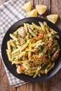 Penne pasta with grilled chicken, greens and lemon sauce close-up. Vertical top view Royalty Free Stock Photo