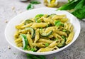 Penne pasta with pesto sauce, zucchini, green peas and basil.