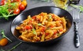 Penne pasta in tomato sauce with meat, tomatoes decorated with pea sprouts