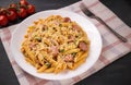 Penne pasta in tomato sauce with sausages and cheese, decorated with parsley on a  black background Royalty Free Stock Photo