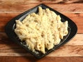 Penne pasta topped with a white creamy sauce and basil served in a plate on a rustic wooden table, selective focus Royalty Free Stock Photo
