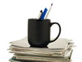 Pens in a coffee mug atop stack of magazines Royalty Free Stock Photo