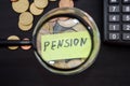 PENSION inscription through a magnifying glass on a background of dollars and coins on a black, wooden table Royalty Free Stock Photo