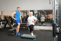 Pensioner, elderly woman in gym on a step platform. Simulator, young coach. Happy smiling people, healthy sports Royalty Free Stock Photo