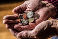 Pensioner man holding in hands euro coins. Theme of low pensions