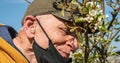 Pensioner with mask removed onto chin smells white flowers