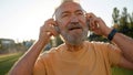 Pensioner put on headphones morning sunrise elderly man listening music technology gadget modern relaxed male cheerful