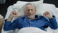 Pensioner stretching in his bed after awakening in the morning, healthy sleep