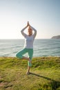 Pensioner woman doing yoga tree pose ocean background Royalty Free Stock Photo