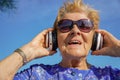 pensioner woman laughs listening music with headphone. Neuronal therapy