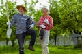 Pensioners caring trees and shovel before planting them near cottage house