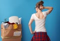 Pensive active woman looking at untidy cardboard box on blue