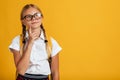 Pensive adolescence european cute schoolgirl with pigtails, backpack in glasses thinks and looks up at free space