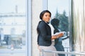 Pensive African American female lawyer in stylish formal suit holding folder with mock up area and looking away standing against Royalty Free Stock Photo