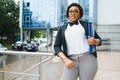 Pensive African American female lawyer in stylish formal suit holding folder with mock up area and looking away standing against Royalty Free Stock Photo
