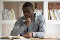 Pensive african American guy reading textbook studying Royalty Free Stock Photo