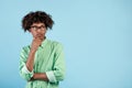 Pensive african american guy thinking over something on blue studio background, looking aside at free space Royalty Free Stock Photo