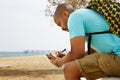 Pensive African-American hipster man wearing backpack and making notes in copybook outside of the city. Student Royalty Free Stock Photo