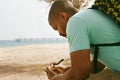 Pensive African-American hipster man wearing backpack and making notes in copybook outside of the city. Student Royalty Free Stock Photo