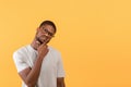 Pensive african american man looking aside at free space and touching chin, thinking about offer over yellow background Royalty Free Stock Photo