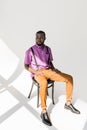 pensive african american man in stylish clothing sitting on chair