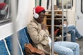 Pensive African young man reading posts, listening music, using smartphone, riding home by subway. Royalty Free Stock Photo