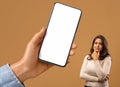 Pensive Arab Woman Looking At Big Blank Smartphone In Huge Female Hand