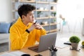 Pensive Asian man using laptop sitting at desk in office Royalty Free Stock Photo