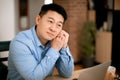 Pensive asian middle aged male freelancer thinking about something, working on laptop at home, copy space Royalty Free Stock Photo