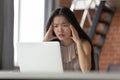 Pensive Asian woman work on laptop think of problem solution